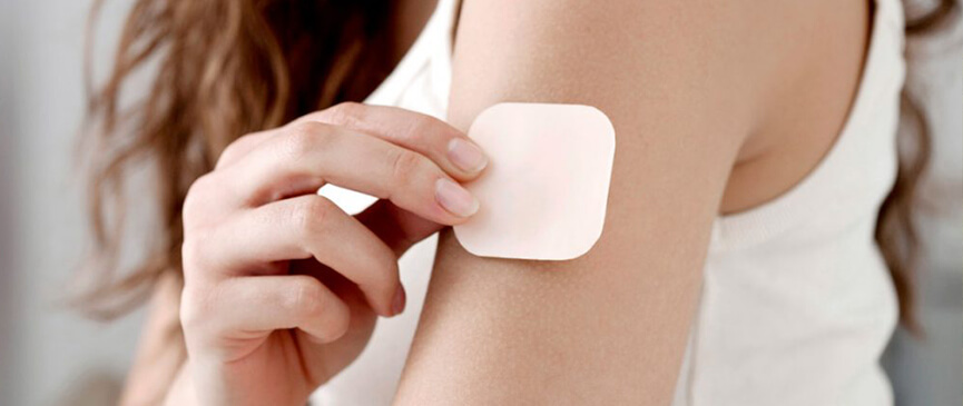 woman applying a transdermal cbd patch to her arm